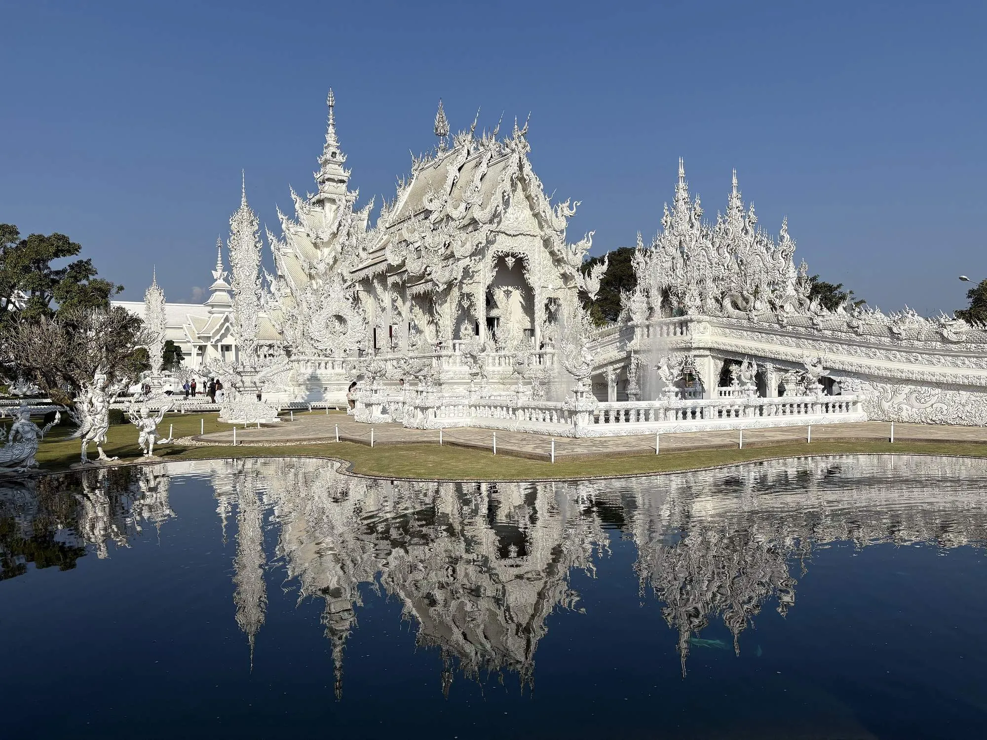 The gleaming white Wat Rong Khun temple reflected in its pond