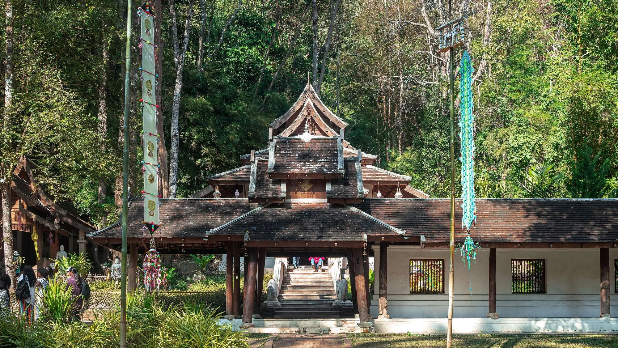 Stone Buddha statues among trees and a stream at Wat Pha Lat